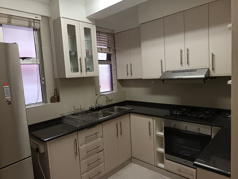 A functional kitchen featuring light-toned cabinetry, dark granite countertops, a built-in oven, gas hob, and an extractor fan.