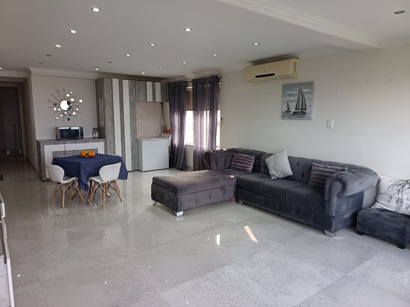 Spacious open-plan living and dining area featuring polished porcelain floor tiles, recessed downlighting, and integrated cabinetry.