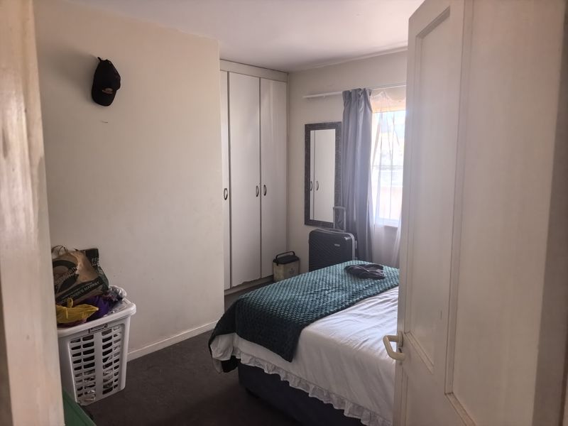 A functional bedroom featuring built-in cupboards and natural light from the window, offering a comfortable space for rest.