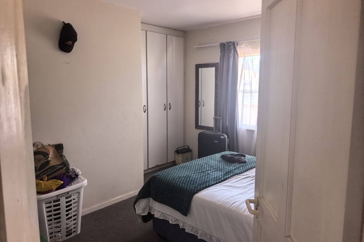 A functional bedroom featuring built-in cupboards and natural light from the window, offering a comfortable space for rest.