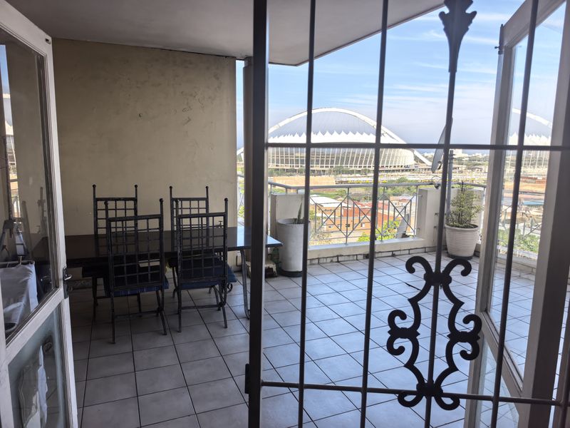 Spacious balcony featuring tiled flooring, a metal security gate, and a balustrade, offering an elevated view of the surrounding area.