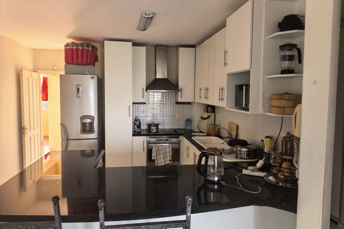 Compact kitchen featuring white cabinetry, granite countertops, stainless steel appliances, and a breakfast bar, providing a functional cooking and dining space.