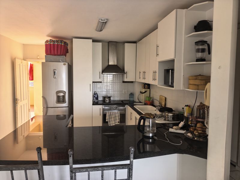 Compact kitchen featuring white cabinetry, granite countertops, stainless steel appliances, and a breakfast bar, providing a functional cooking and dining space.
