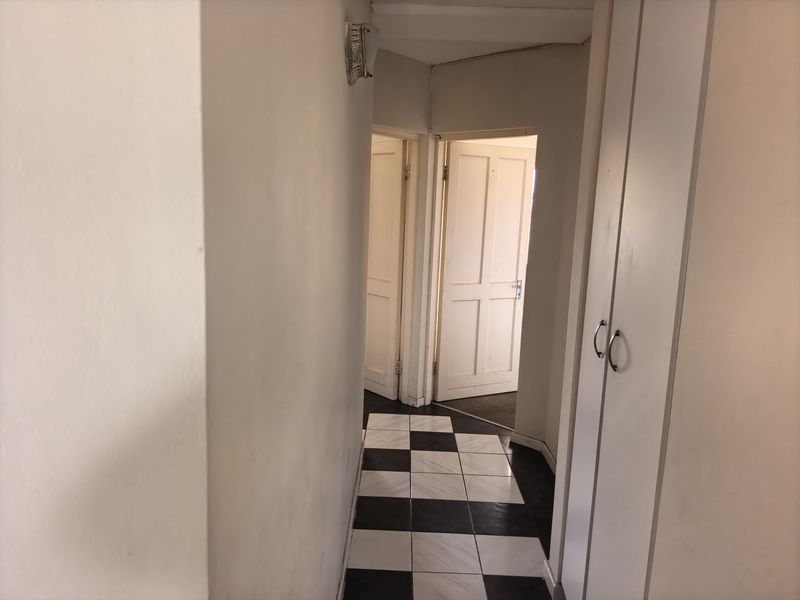 A functional hallway featuring built-in storage cupboards, tiled flooring, and access to adjacent rooms through internal doors.
