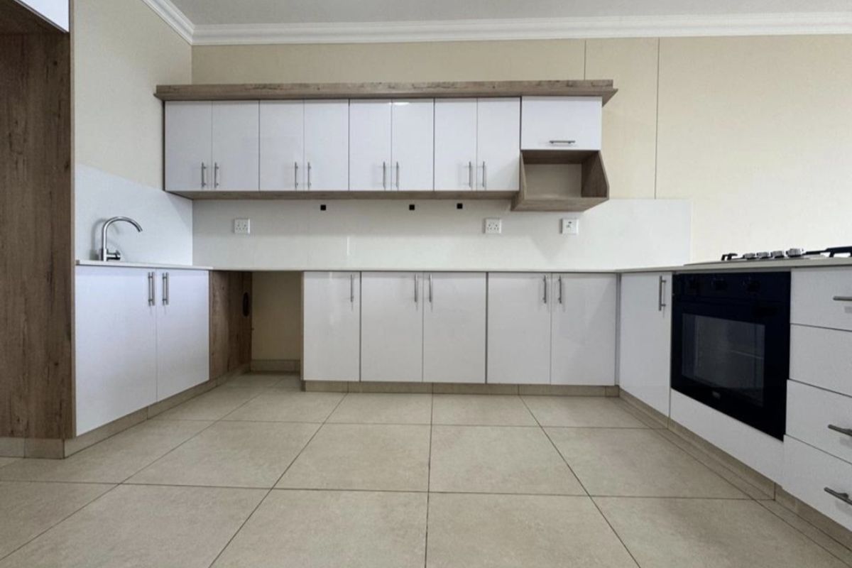 Modern kitchen featuring white cabinetry, wood-look accents, tiled flooring, and integrated oven and hob, offering a clean and functional workspace.