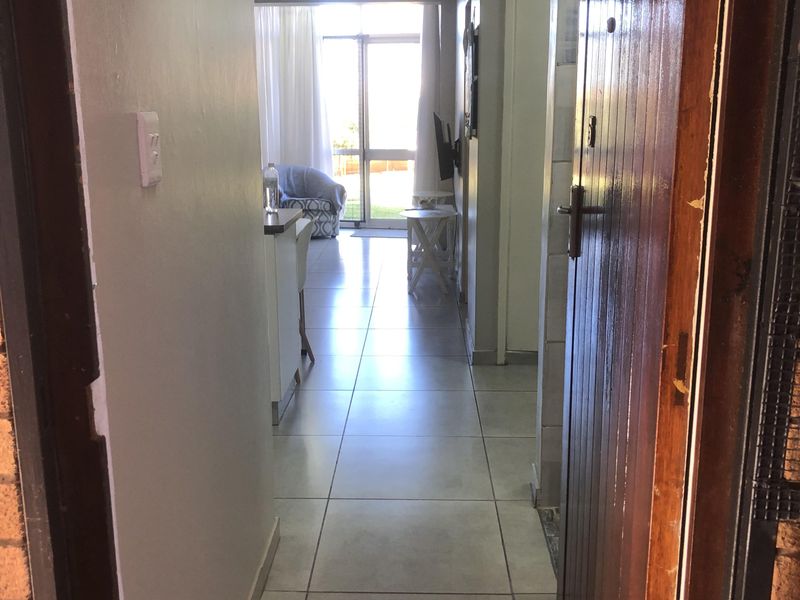 Entrance hallway featuring tiled flooring leading into an open-plan living area with access to a sliding glass door.