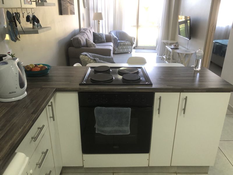 Open-plan kitchen featuring a built-in oven, electric hob, and laminate countertops, flowing into a combined living and dining area with access to a patio.