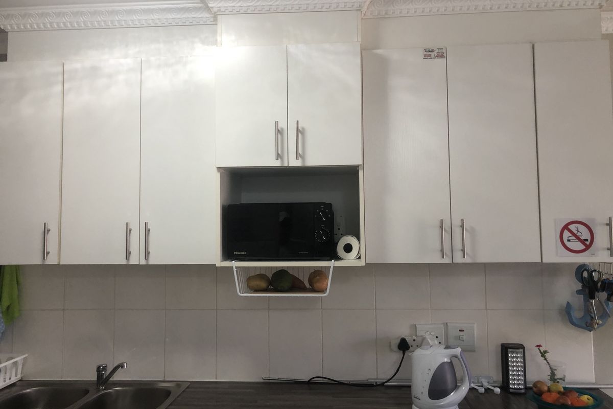 A functional kitchen area featuring white built-in cabinetry, a double bowl stainless steel sink, laminate countertops, and classic crown molding detail.