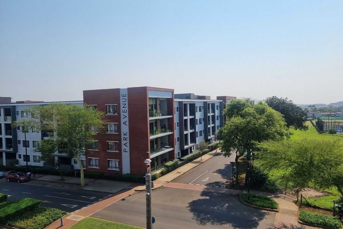 Aerial view of the Park Avenue apartment complex, showcasing the brick facade, balconies, and surrounding landscaped grounds and access roads.