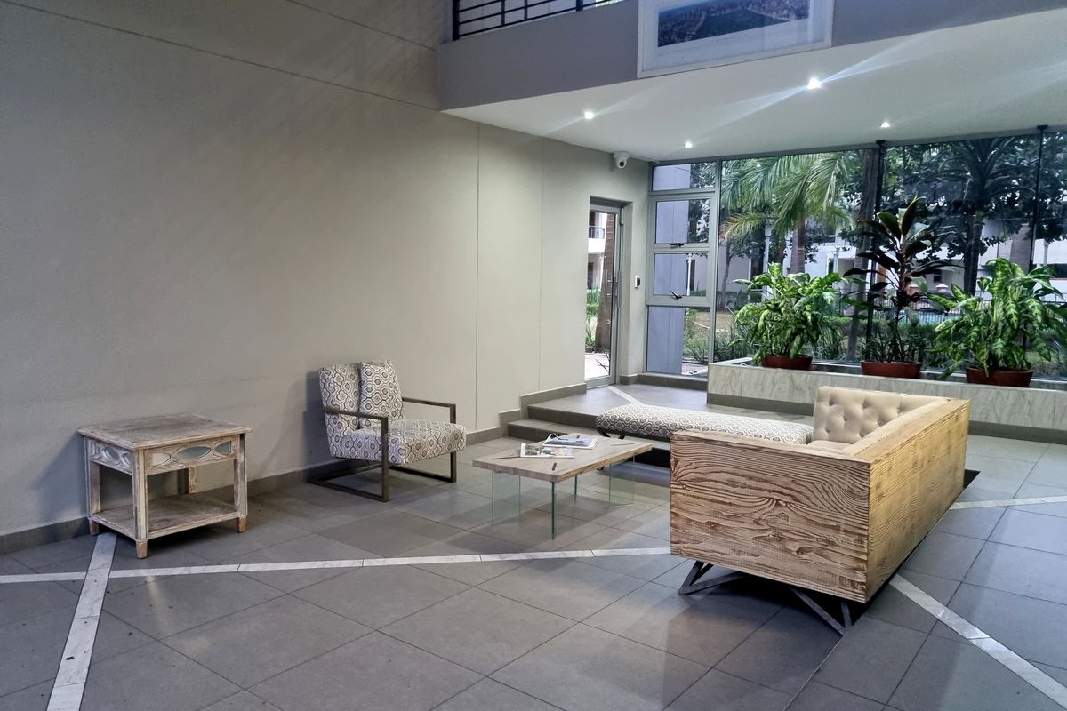 A spacious, modern living area featuring double-volume ceilings, large glass windows, and tiled flooring with a contemporary open-plan layout.