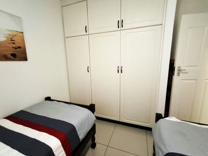 A bedroom featuring built-in cupboards with overhead storage and tiled flooring.