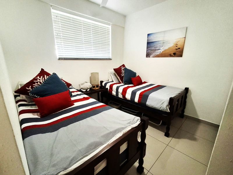 A functional bedroom featuring tiled flooring and venetian blinds, providing a clean and simple space for rest.