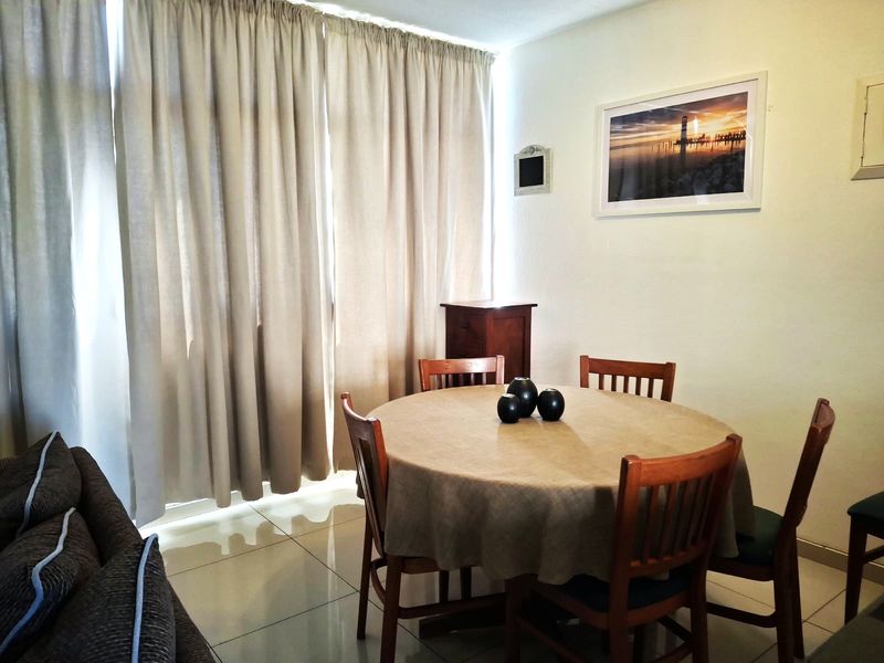 A dining area featuring neutral tiled flooring and full-length curtains, providing a functional space for meals.