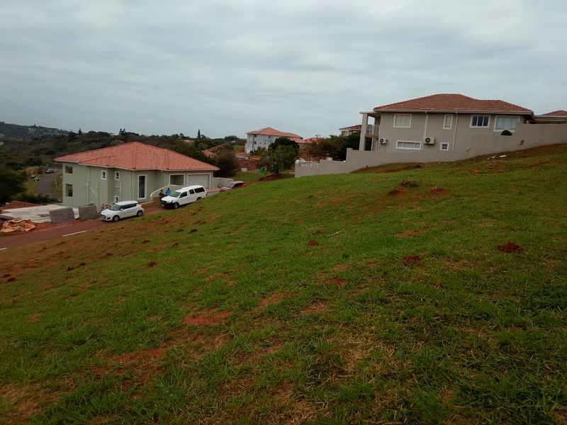 A view of a sloped residential plot overlooking neighboring houses in a suburban estate setting.