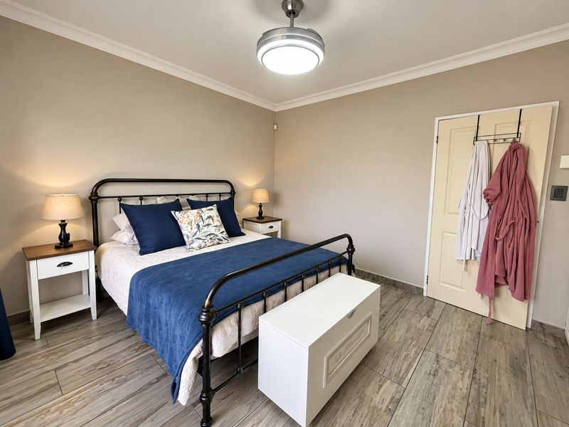 A well-maintained bedroom featuring neutral wall tones, durable tiled flooring, and a central ceiling fan, offering a clean and comfortable living space.