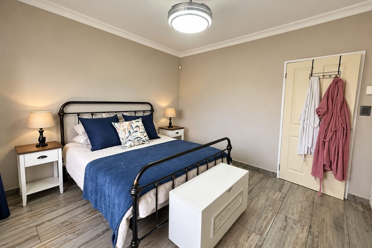 A well-maintained bedroom featuring neutral wall tones, durable tiled flooring, and a central ceiling fan, offering a clean and comfortable living space.