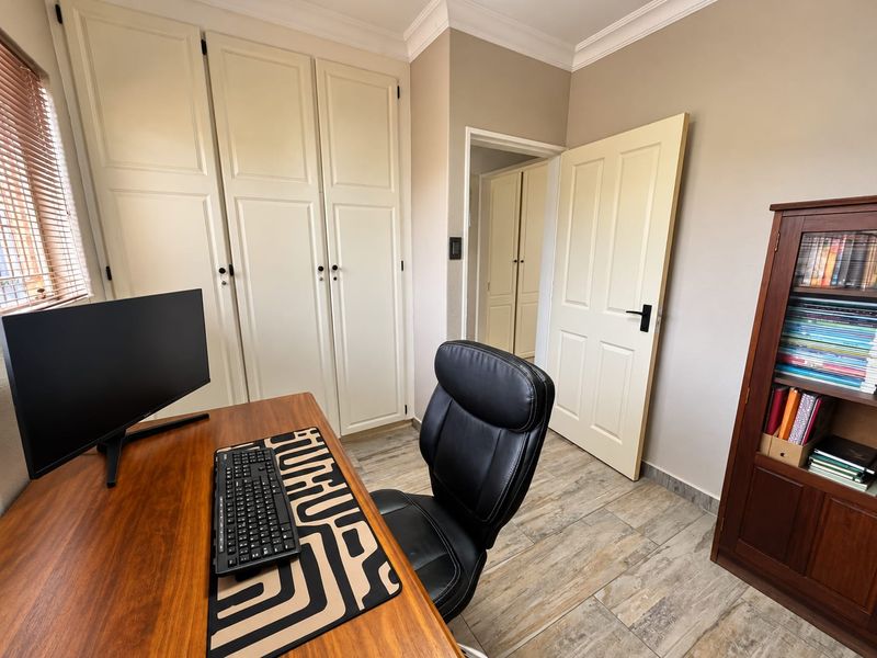 A functional home office featuring built-in storage cupboards, tiled flooring, and neutral wall finishes, providing a clean and organized workspace.