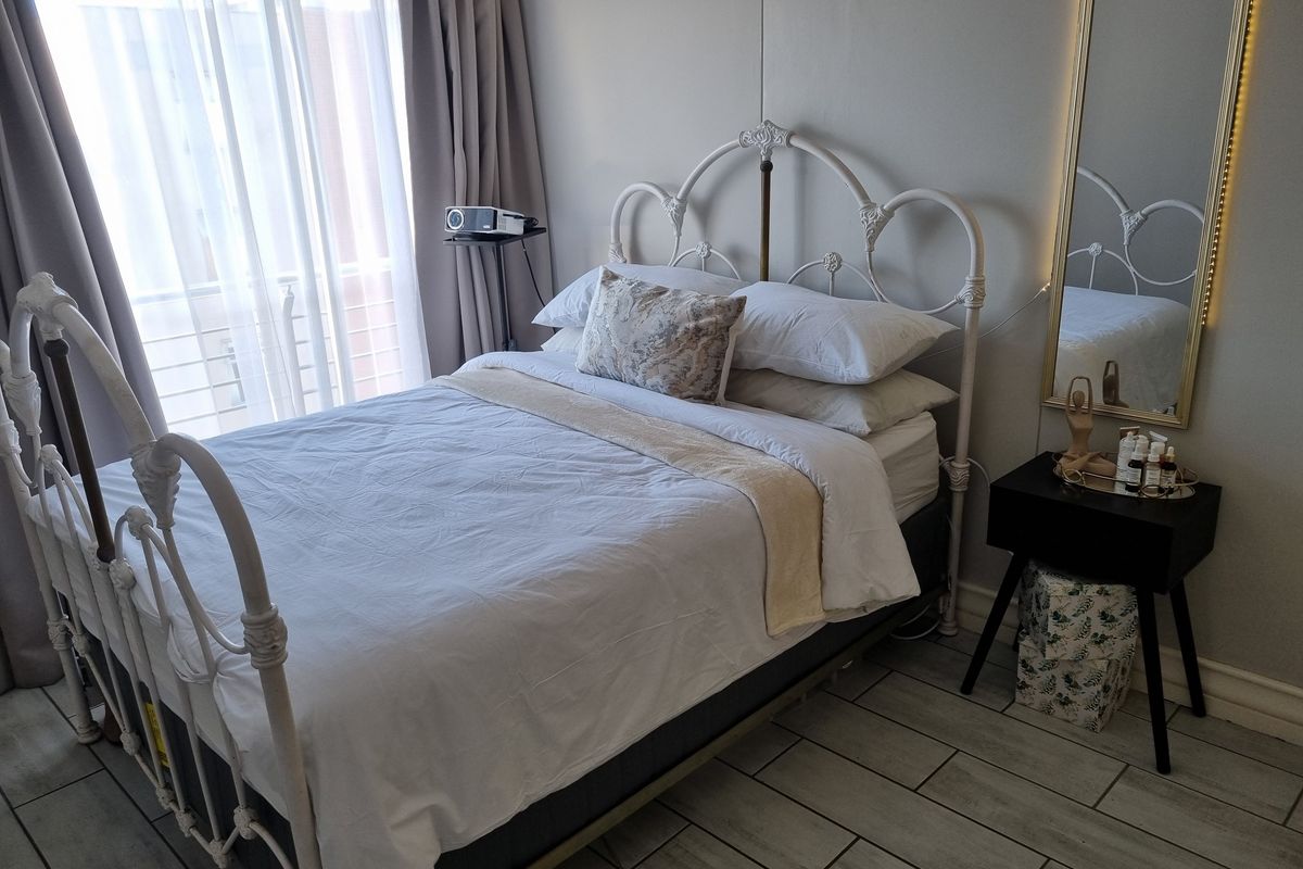 A well-lit bedroom featuring tiled flooring and a large sliding glass door with curtains, providing access to an outdoor area.
