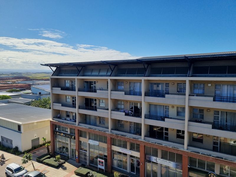 Exterior view of a multi-story apartment building featuring residential balconies above ground-floor commercial retail spaces.