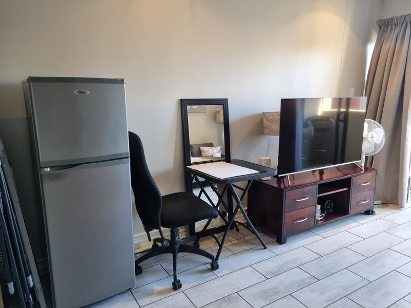 A living area featuring light-colored tiled flooring and neutral wall finishes, providing a functional space for daily living.
