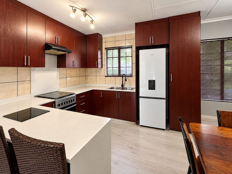 Modern kitchen featuring dark wood cabinetry, stone countertops, stainless steel stove, extractor fan, and tiled backsplash with integrated appliance space.