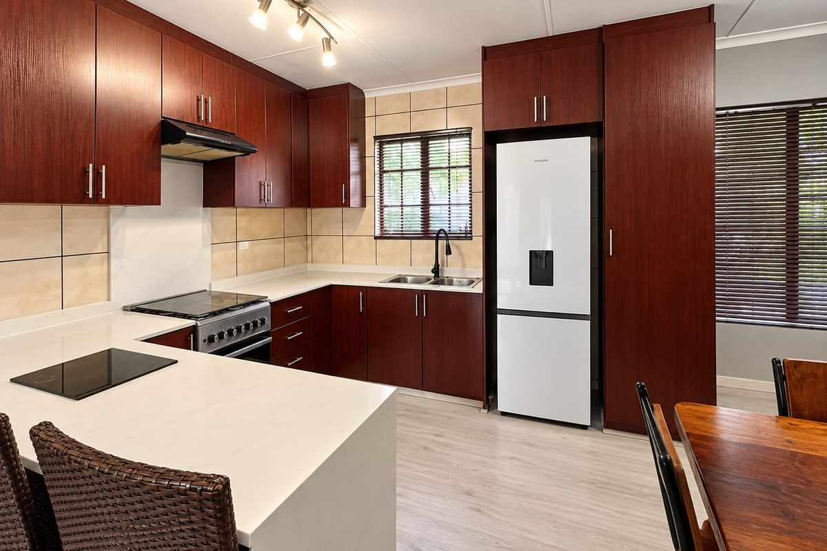Modern kitchen featuring dark wood cabinetry, stone countertops, stainless steel stove, extractor fan, and tiled backsplash with integrated appliance space.