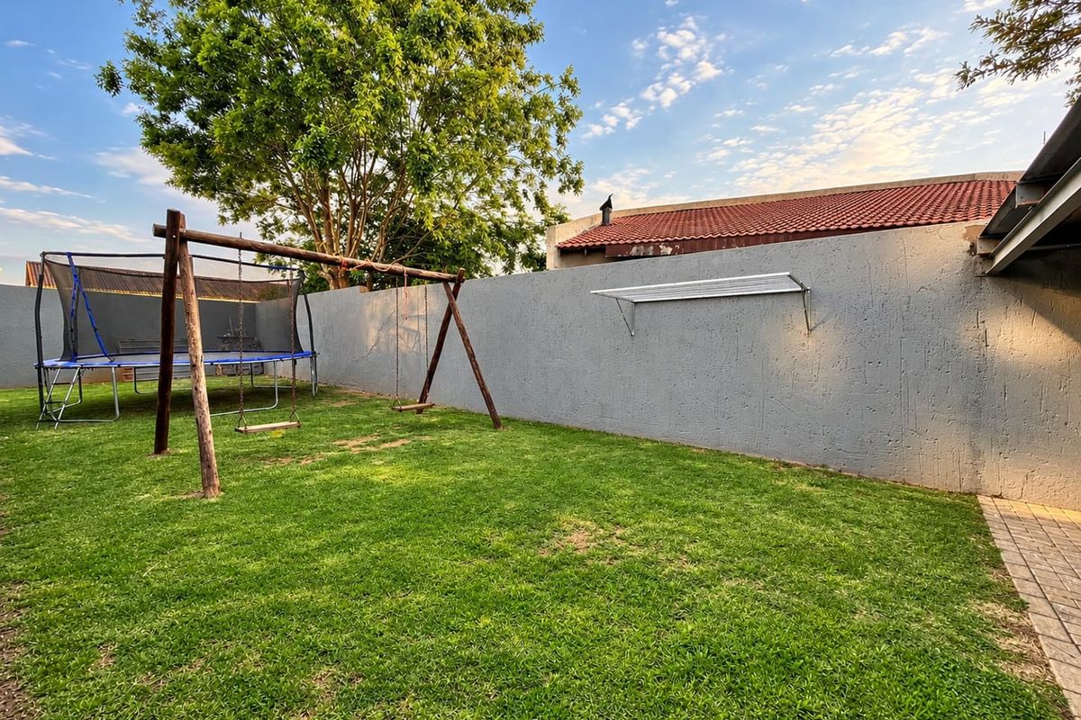 A private rear garden featuring a lawn, perimeter wall, and wall-mounted clothesline, providing a functional outdoor space.