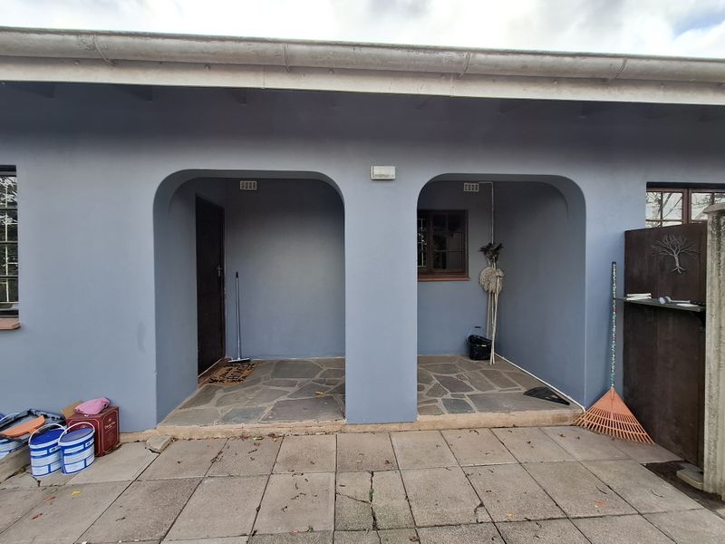 A covered patio area featuring stone flooring and arched architectural details, providing a functional outdoor space.
