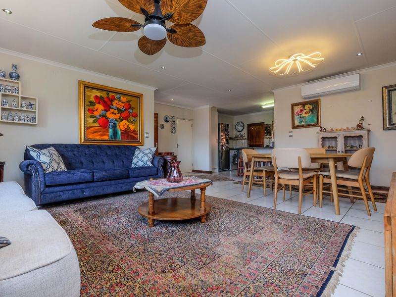 Spacious open-plan living and dining area featuring tiled flooring, a ceiling fan, and a wall-mounted split system air conditioner for climate control.