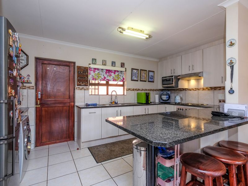 A functional kitchen featuring granite countertops, ample cabinetry, tiled flooring, and a breakfast bar, providing a practical space for daily meal preparation.