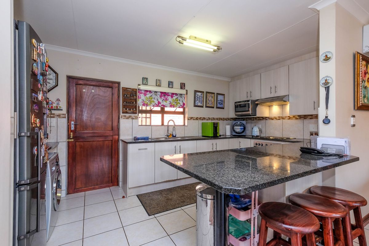 A functional kitchen featuring granite countertops, ample cabinetry, tiled flooring, and a breakfast bar, providing a practical space for daily meal preparation.