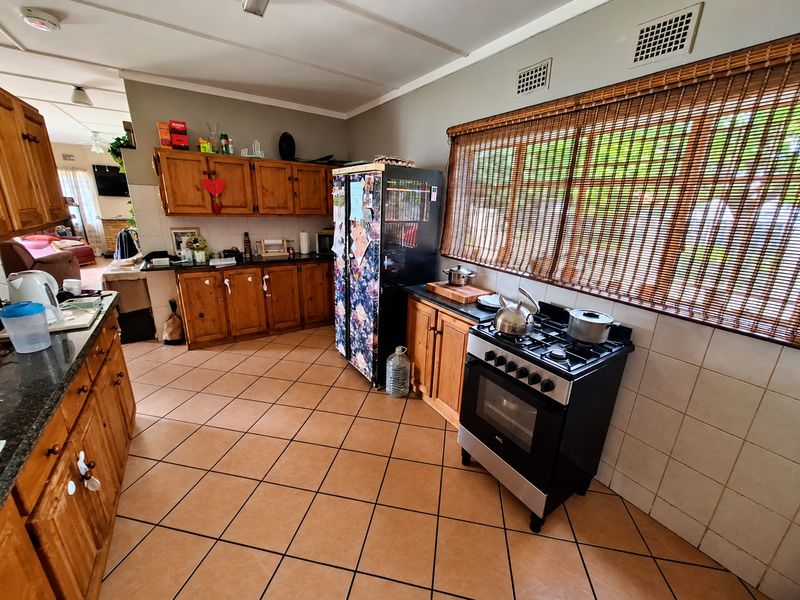 A functional kitchen featuring wooden cabinetry, granite countertops, a gas stove with oven, and tiled flooring, offering a classic and practical layout.