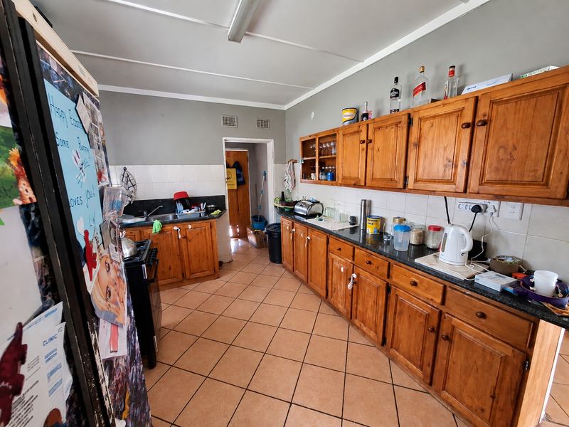 A functional kitchen featuring wooden cabinetry, granite countertops, and tiled flooring, offering a traditional layout with ample storage space.