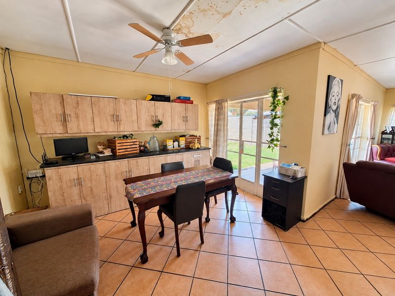 Open plan living and dining area featuring tiled floors, built-in cabinetry, and a ceiling fan, with direct access to the rear garden.
