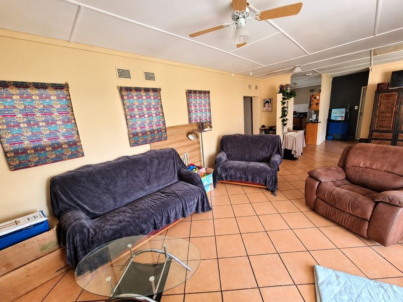 Open plan living area featuring ceramic tiled flooring, a ceiling fan, and direct access to the kitchen area.