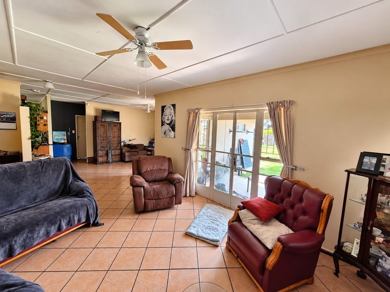 Spacious living area featuring tiled flooring, a ceiling fan, and glass sliding doors providing access to the outdoor patio.