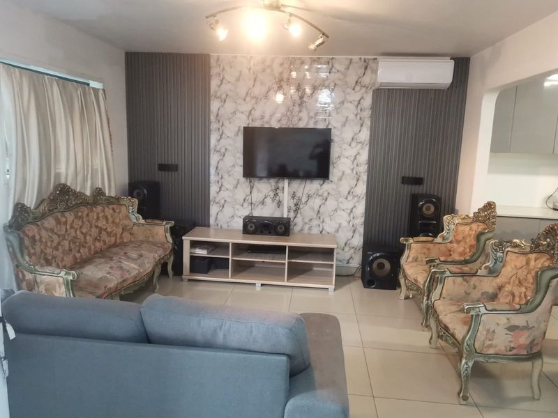 Living room featuring a marble-effect feature wall with vertical slat paneling, tiled flooring, and a wall-mounted air conditioning unit.