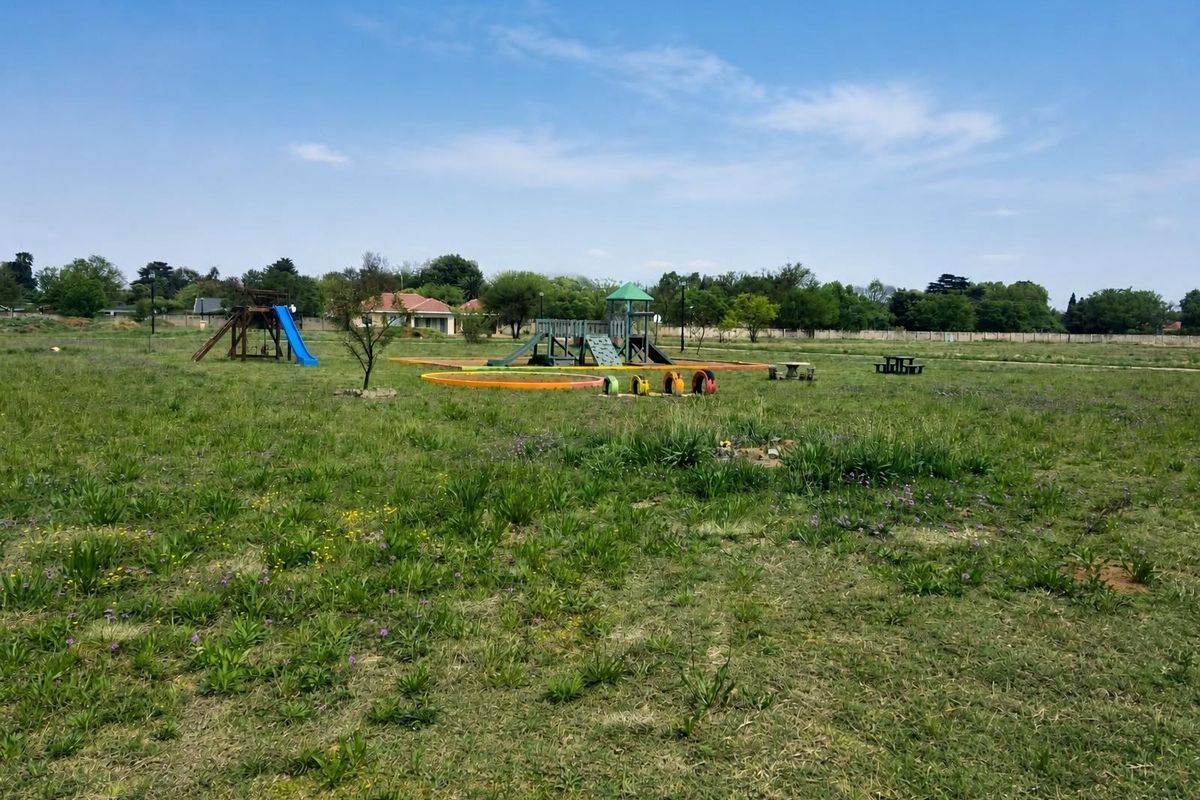 A spacious residential garden area featuring an established playground set and open grass lawn.
