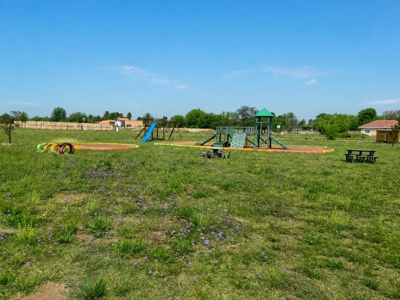A spacious residential garden area featuring established playground equipment and open green space.