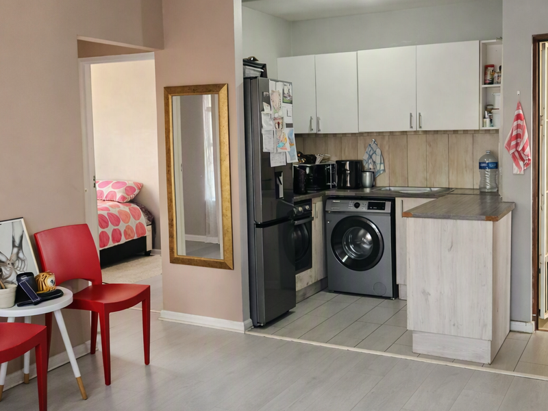 Open-plan kitchen area featuring built-in cabinetry, tiled backsplash, and integrated appliances, seamlessly connected to the living space and adjacent bedroom.
