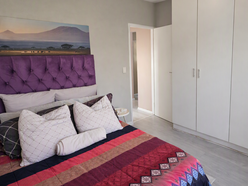 A well-maintained bedroom featuring neutral walls, light laminate flooring, and ample built-in cupboard storage.