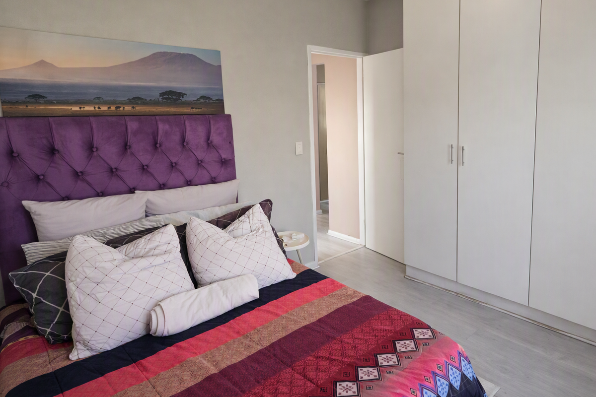 A well-maintained bedroom featuring neutral walls, light laminate flooring, and ample built-in cupboard storage.