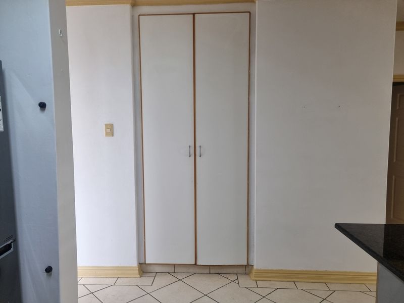 A functional hallway area featuring built-in storage cupboards and tiled flooring, providing practical storage space within the apartment.