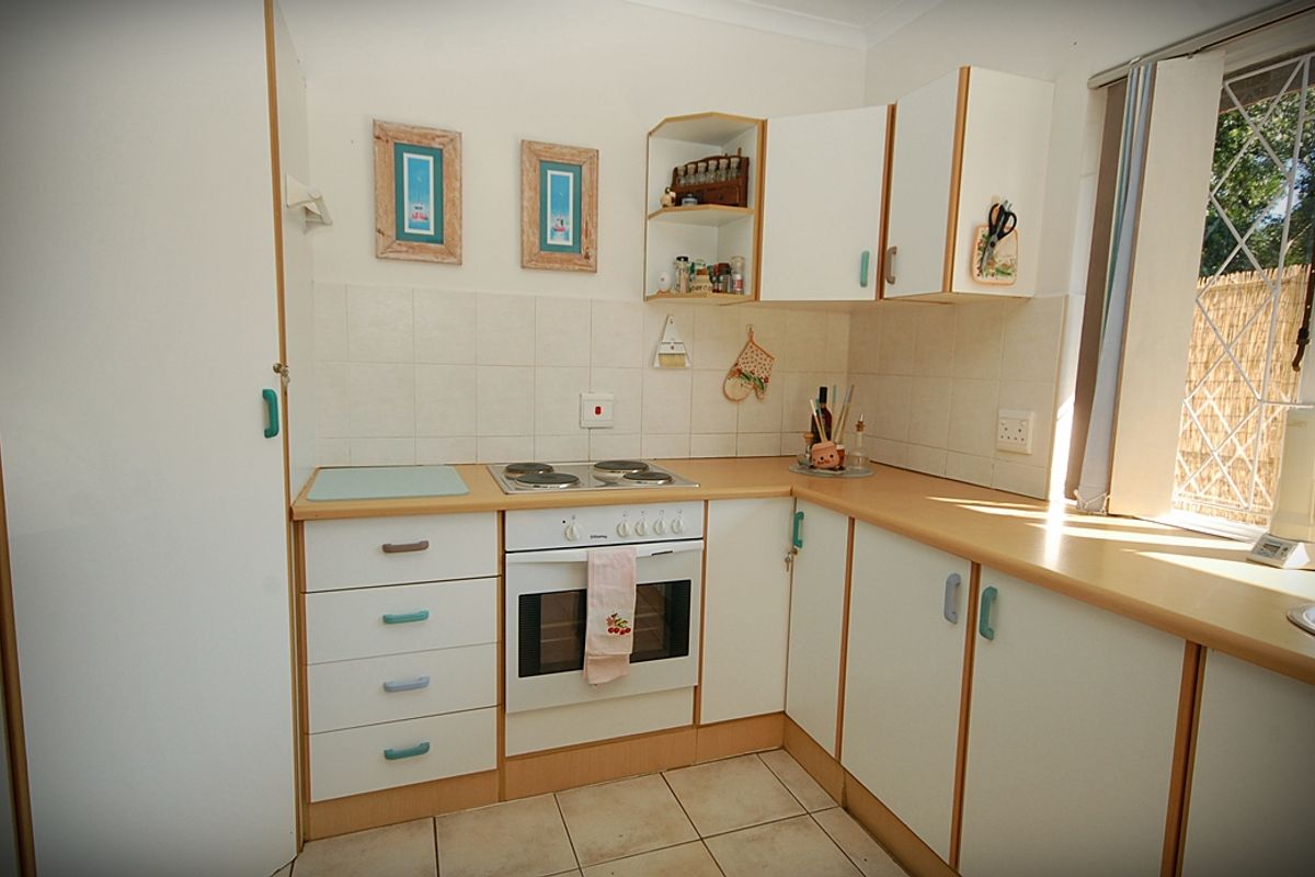 A functional kitchen featuring laminate countertops, tiled backsplash, built-in oven, electric cooktop, and ample cabinetry storage.