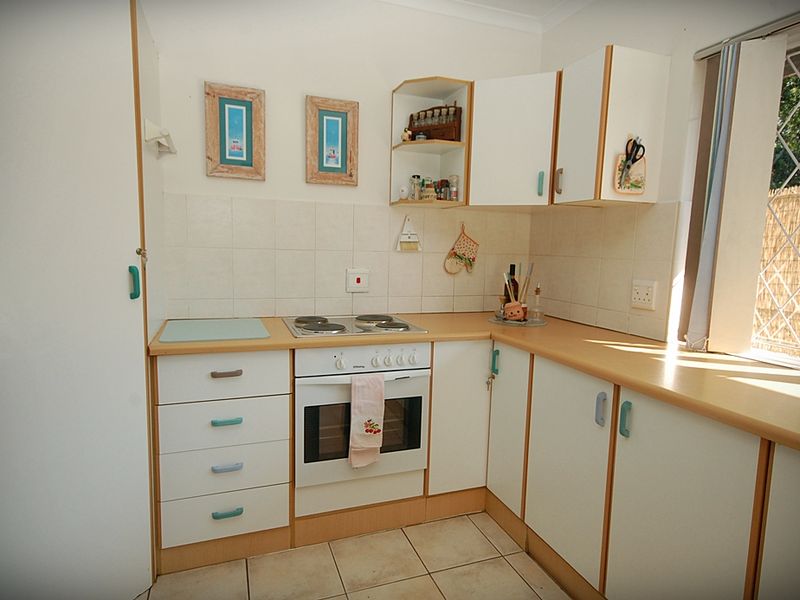 A functional kitchen featuring laminate countertops, tiled backsplash, built-in oven, electric cooktop, and ample cabinetry storage.