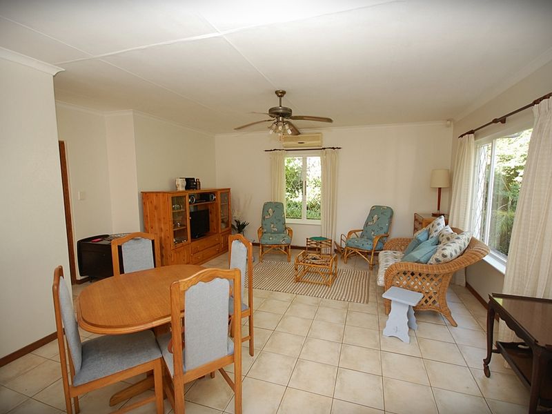 Open plan living and dining area featuring tiled flooring, a ceiling fan, and a wall-mounted air conditioning unit.