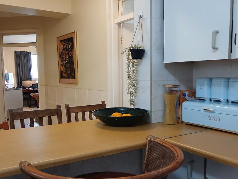 A functional kitchen area featuring laminate countertops, built-in cabinetry, and tiled splashbacks, with an open flow into the adjacent living space.