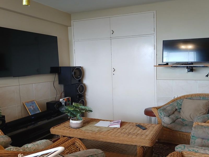 A living room featuring a built-in storage cupboard and tiled wall accents, providing a functional space for relaxation.
