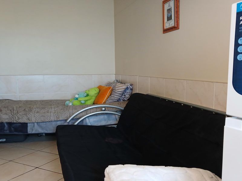 A bedroom featuring ceramic floor tiles and partial wall tiling, providing a functional and easily maintainable living space.