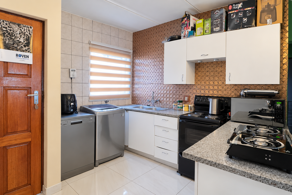 A functional kitchen featuring white cabinetry, granite countertops, a double sink, and a tiled backsplash, with space for under-counter appliances.